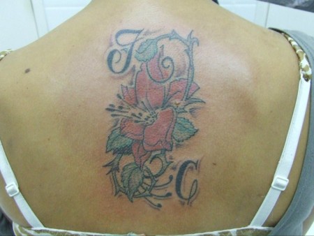Tatuaje de una mujer de unas iniciales con una flor