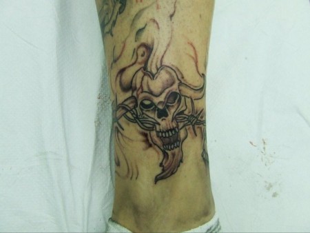 Tatuaje de un brazalete formado por alambre de espinos y una calavera con cuernos