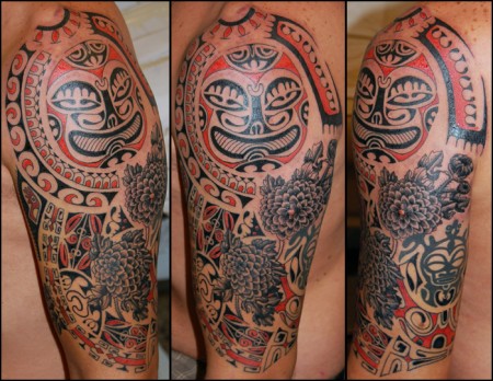 Tatuaje de mascaras maorí y flores en el brazo