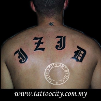 Tatuaje de unas letras góticas en la espalda y una pequeña letra china en la nuca