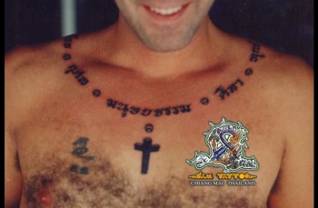 Tatuaje de una frase tailandesa rodeando el cuello y una cruz
