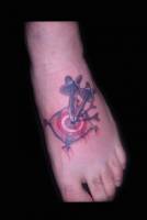 Tatuaje de una diana con dos dardos. Tatuaje en el pie