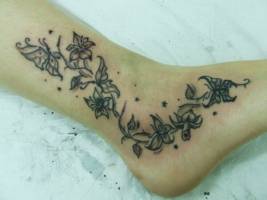 Tatuaje de flores y mariposas en el pie