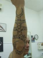 Tatuaje de un tribal extraterrestre agarrando en el brazo