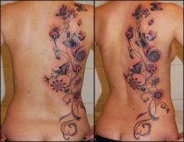 Tatuaje de una planta con flores y mariposas en la espalda de una mujer