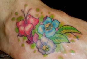 Tatuaje de flores con sus hojas en el pie