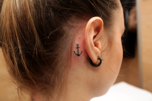 Tatuaje de una pequeña ancora detrás de la oreja