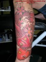 Tatuaje de dos carpas entre flores y agua en el antebrazo