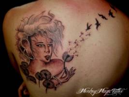 Tatuaje de una chica soplando una flor de donde salen golondrinas