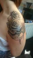 Tatuaje de flores en blanco y negro en el hombro de una chica