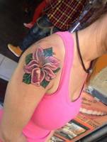 Tatuaje de una gran flor a color en el hombro de una mujer