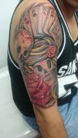 Tattoo a color en el brazo de calaveras mexicanas con un as de poker y rosas 