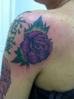 Rosa tatuada detrás del hombro